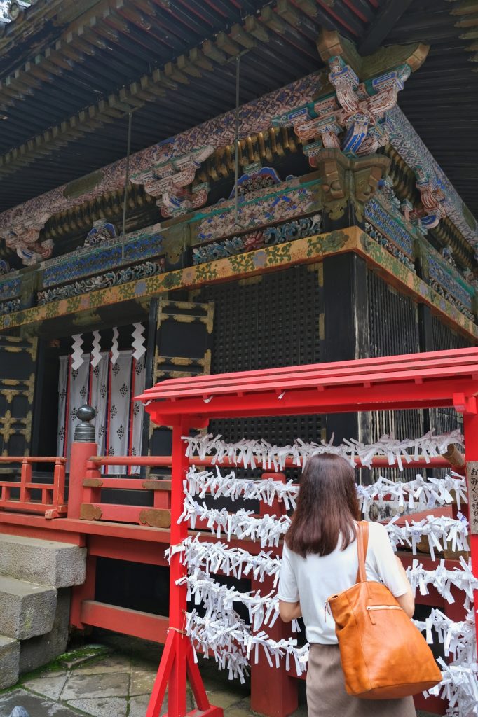 Une dame accroche sa prière dans un temple de Nikko