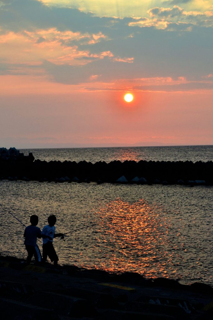 Des enfants pêchent devant le coucher de soleil