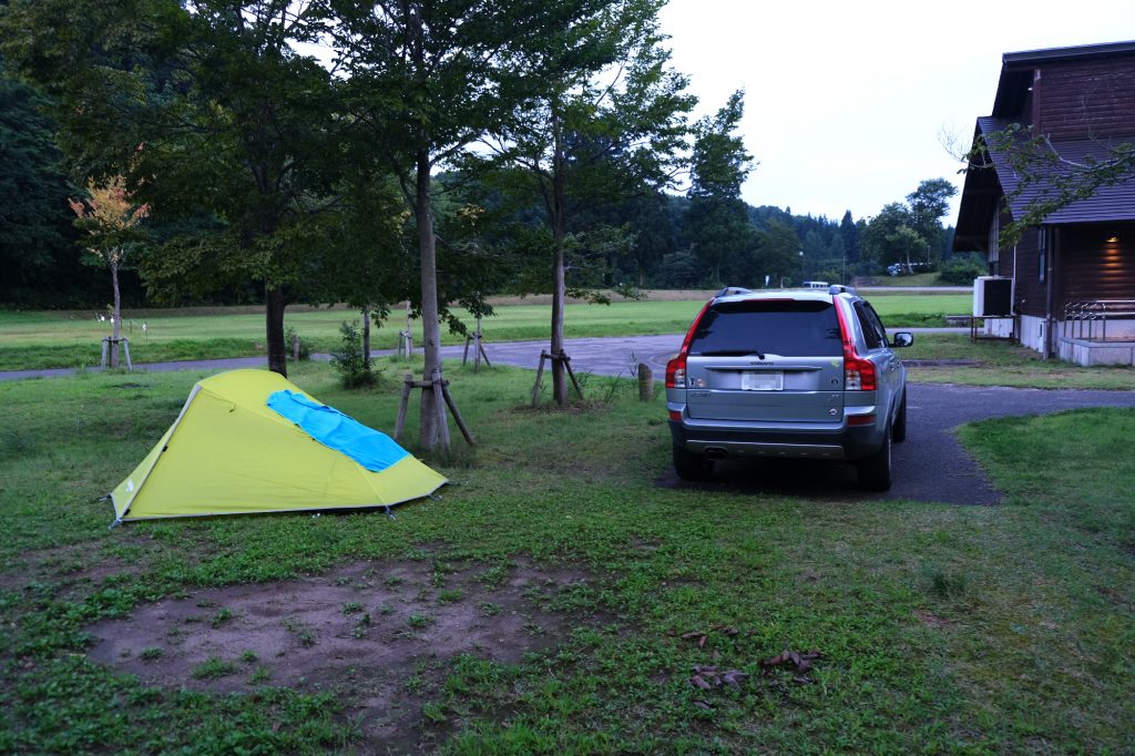 Un camping payant avec place pour la voiture à côté de la tente