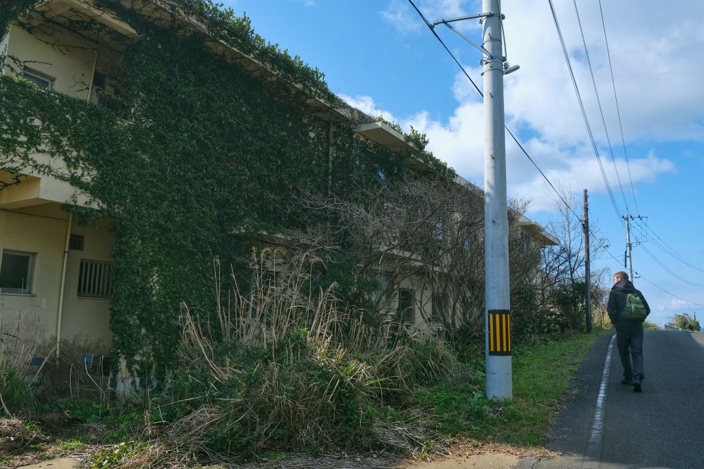 Vincent passe à côté d'un petit immeuble abandonnée d'Ikeshima
