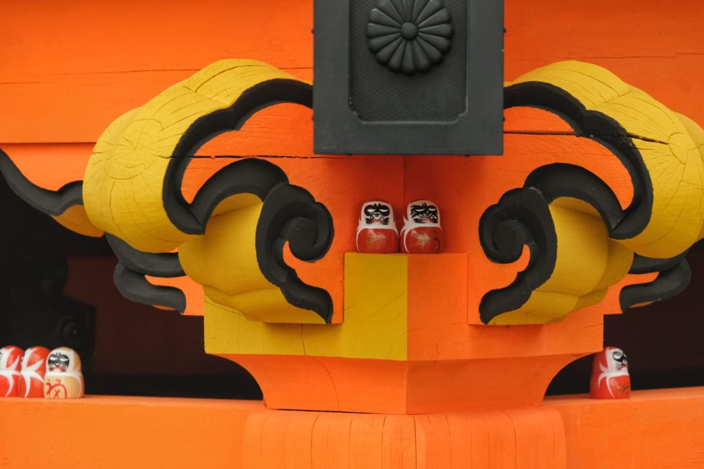 Un couple de daruma entre les poutres d'un bâtiment du Katsuo-ji de Minoo