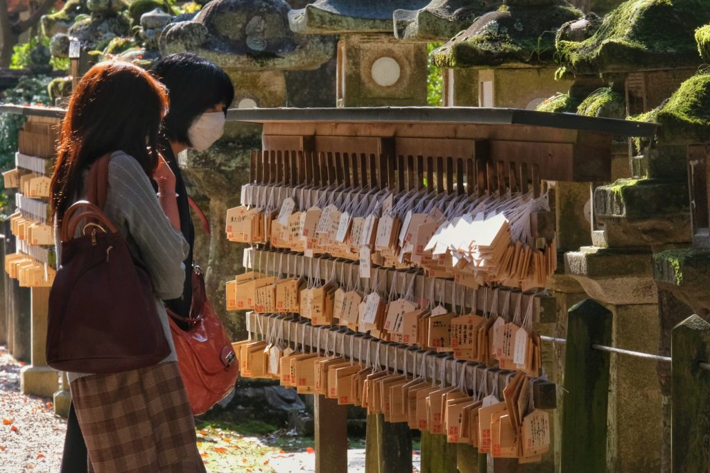 Des visiteurs devant les ema d'un sanctuaire près du Kasuga Taisha de Nara